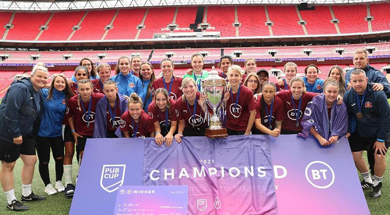 Saddiqa, teammates and coaches celebrate a success with the trophy on the Wembley pitch